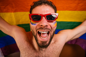 Happy man celebrating pride parade with rainbow flag, a Photo by karrastock