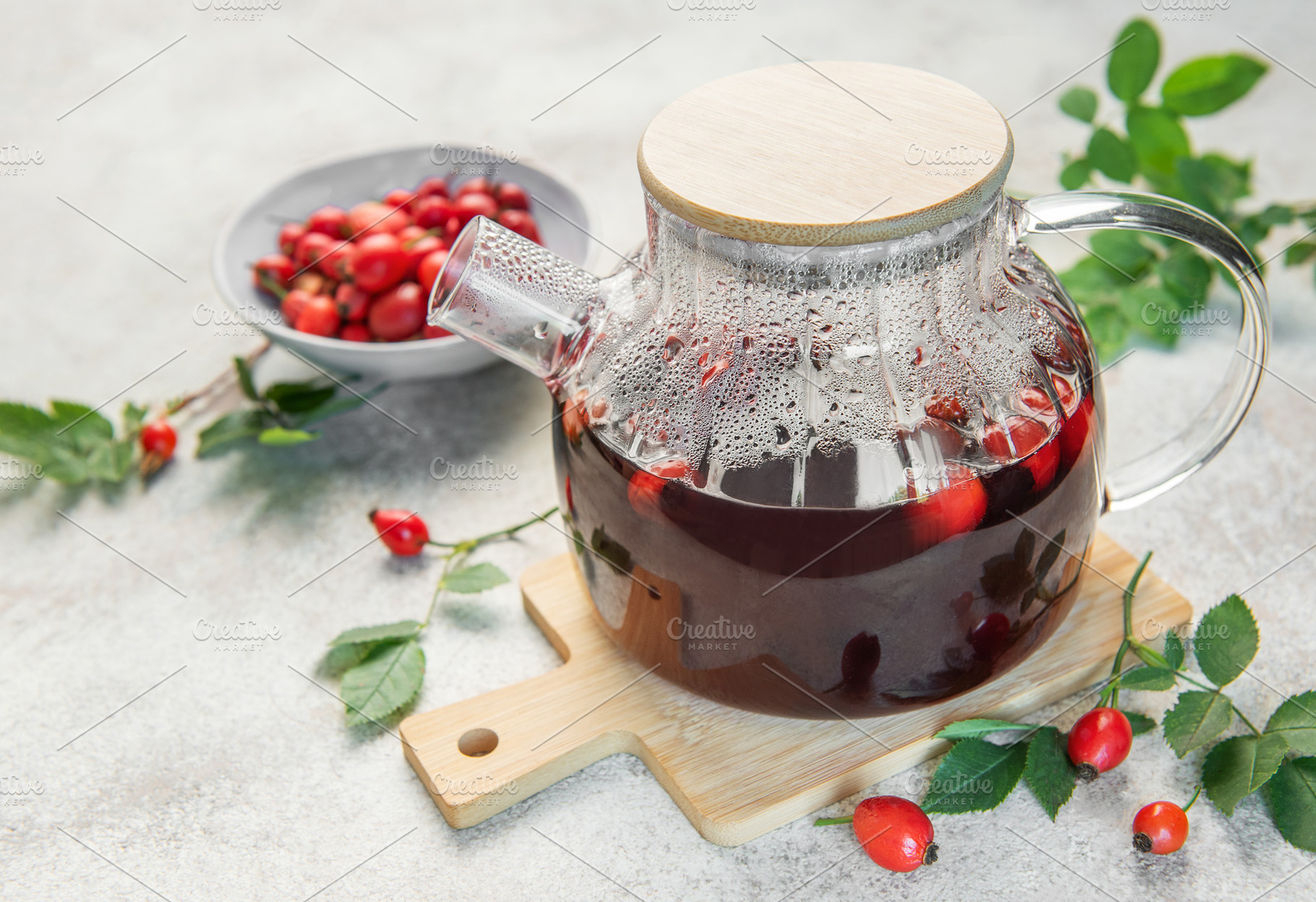 Steaming rosehip tea brewing in glass teapot on wooden board, a Food & Drink Photo by Olena Rudo