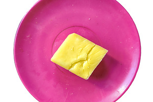 Piece of low-fat cheese placed on a red plastic plate isolated p, a Food & Drink Photo by DanFLCreativo