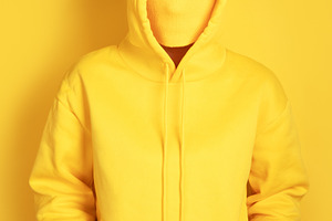 Faceless individual wearing a yellow hoodie against a yellow bac, a Person Photo by Ales Munt