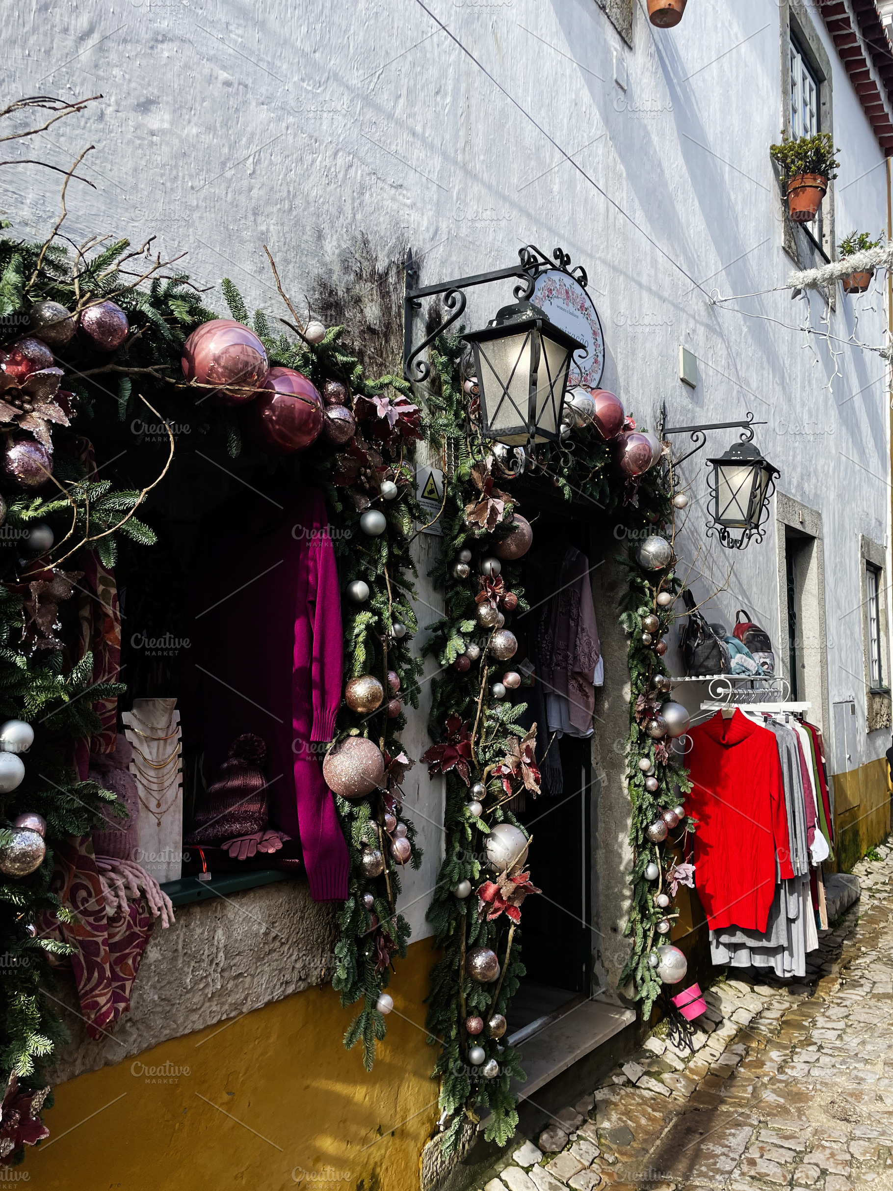 Festive decorated storefront on a cobblestone street in Óbidos, Portugal, a Photo by AS photostudio