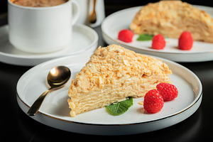 Sliced Napoleon cake on a white wooden table. Classic dessert, a Food & Drink Photo by Budarinphoto