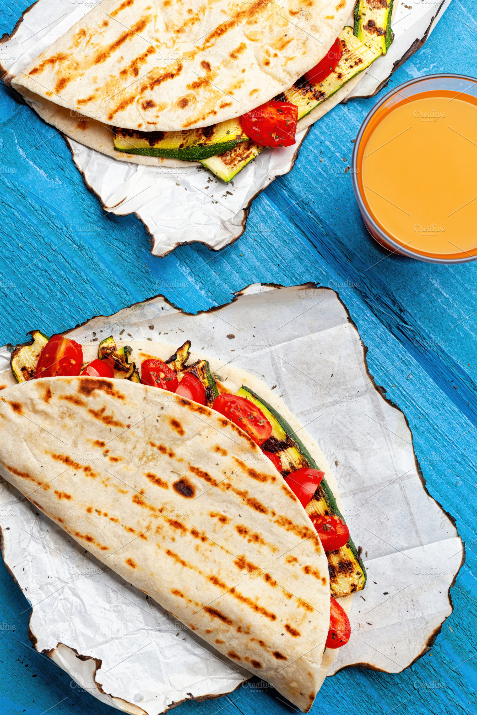 Piadina with grilled zucchini and tomatoes served with orange juice for a vegan, a Food & Drink Photo by Antonio Gravante Market