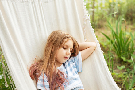 A little girl rests in a hammock and eats cherries in the summer, a Sports & Recreation Photo by Olena Rudo