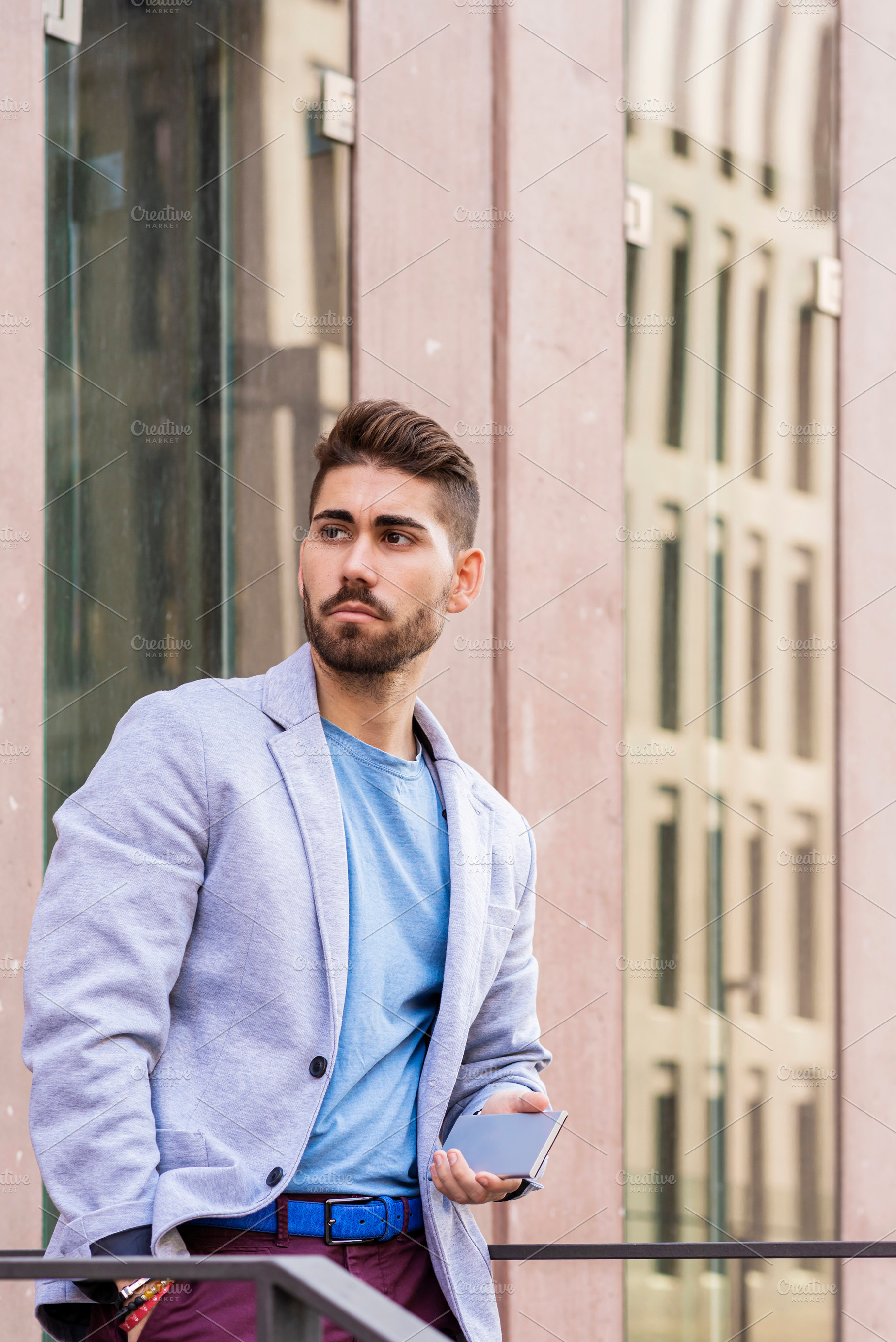 Portrait of outgoing bearded male holding a mobile while looking away outdoor, a Person Photo by RF Images