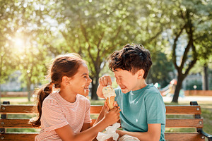 Children sharing ice cream in a park, a Person Photo by DanFLCreativo