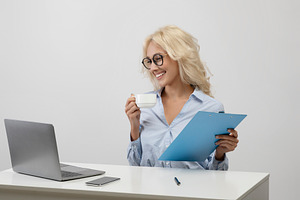Business lifestyle. Happy office worker drinking coffee, working with documents, a Photo by Prostock-Studio