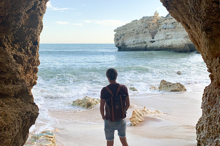 A person stands barefoot on the sandy shore, admiring the coasta
