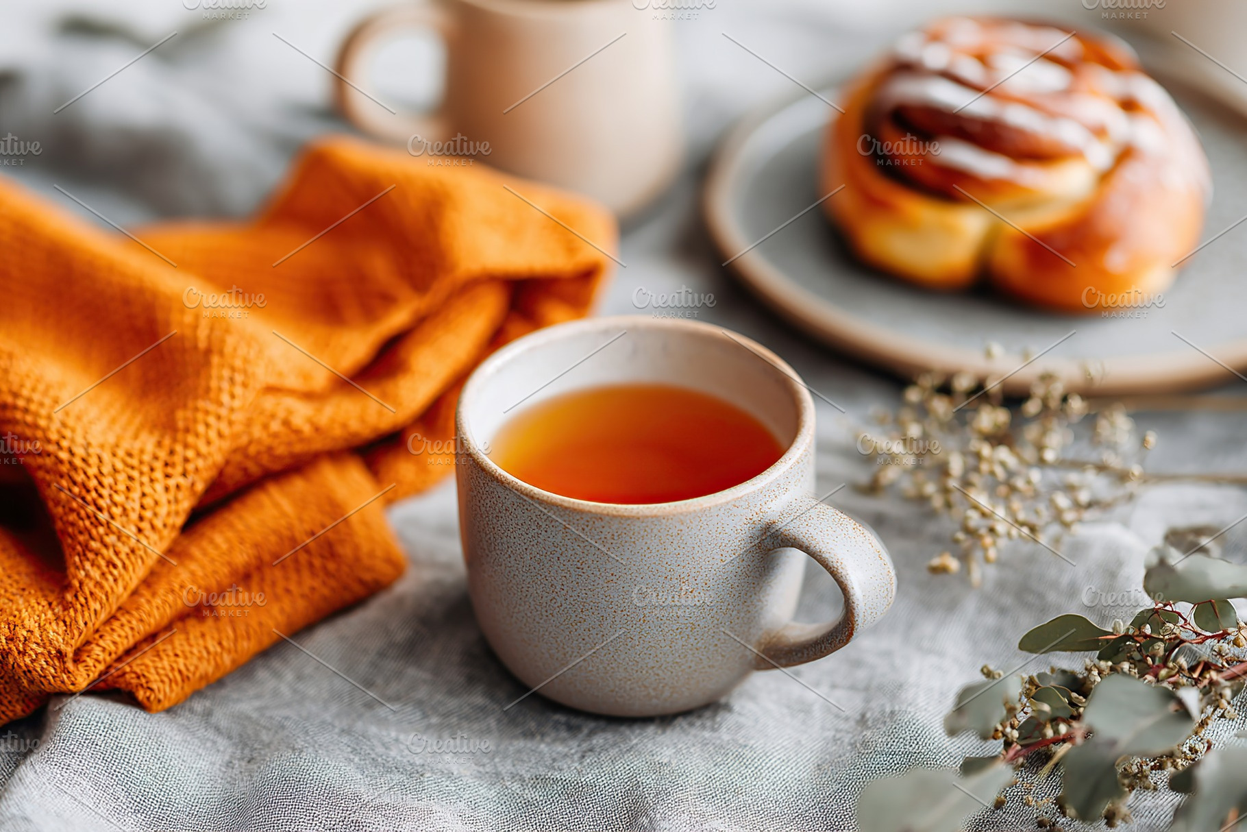Warm tea on a cozy dining table with a sweet cinnamon roll and a soft blanket, a Food & Drink Photo by AlyaAnd
