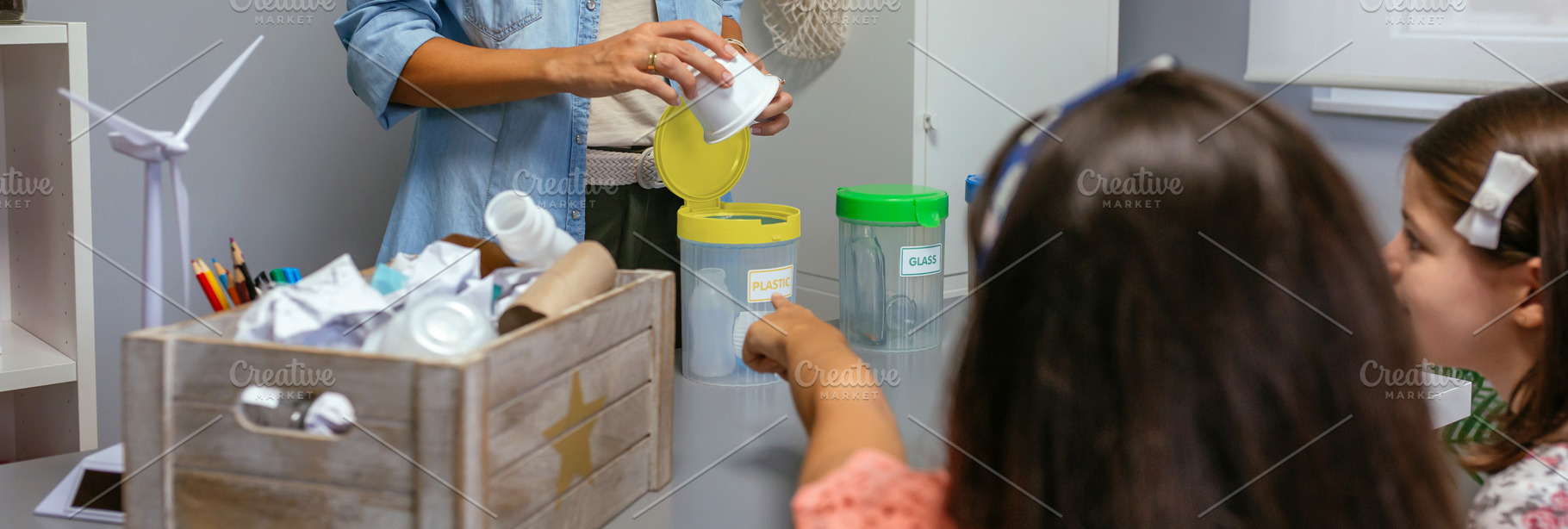 Girl pointing recycle box while female teacher holding plastic pack, a School & Education Photo by davidpereiras