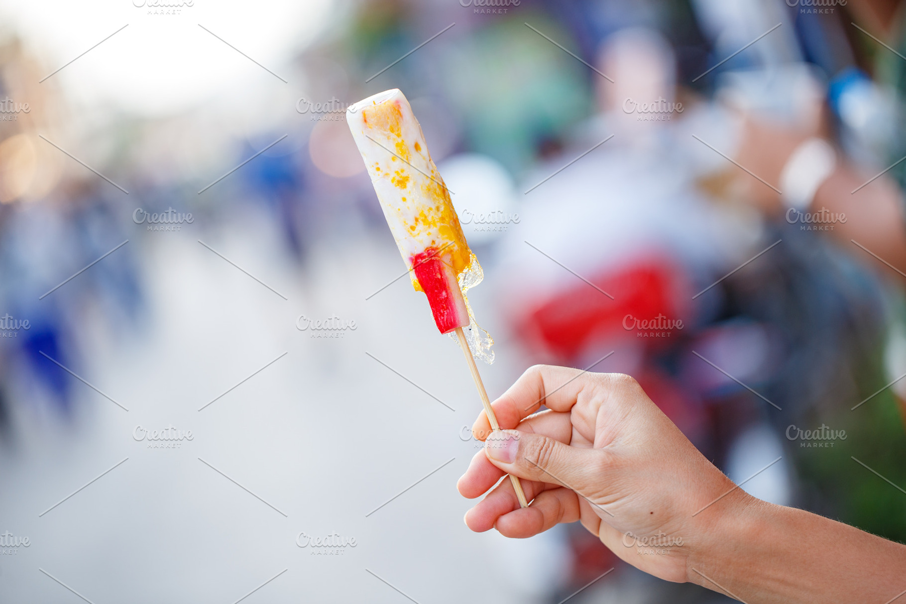 Delicious ice cream on stick held by hand in vibrant setting, a Food & Drink Photo by a454