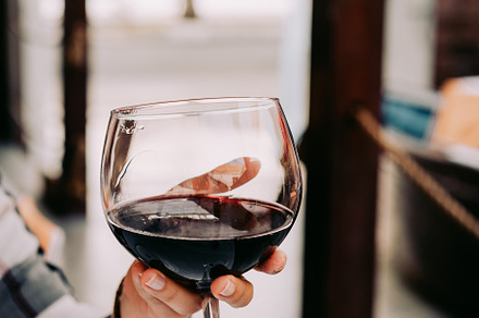 Woman hand holding a wine glass with red wine featuring wine, glass, and red, a Food & Drink Photo by Igor Tichonow