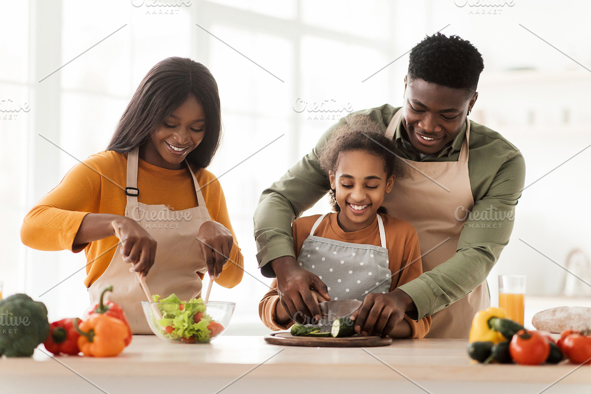 Joyful Black Family Making Fresh Vegetable Salad In Modern Kitchen, a Photo by Prostock-Studio (Photo 1 of 2)