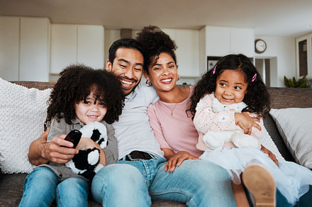 Portrait of mom, dad and kids on sofa, watching tv and happy family bonding together in living room. Smile, happiness and parents relax with children on couch, streaming television show or movies., a Photo by Peopleimages.com