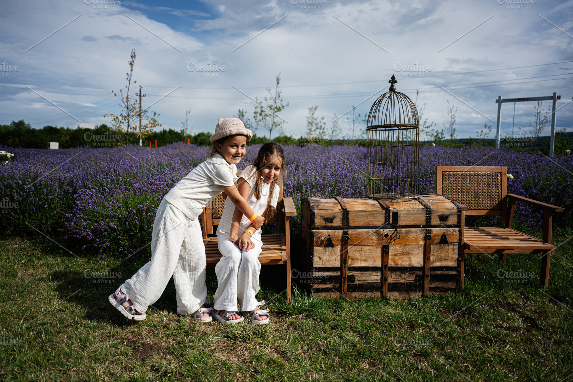 Children playing in a lavender field with wooden chest and chairs, a Photo by AS photostudio