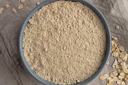 Organic White Oat Flour in a Bowl on a gray background, top view, a Food & Drink Photo by LiudmylaChuhunova
