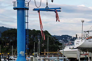 Blue dry dock crane in a marina with, an Industrial Photo by Perpis