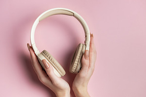 Woman holding wireless headphones on pink background, a Technology Photo by Olena Rudo
