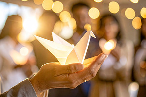 Business leader holding a glowing origami bird close to chest, a Technology Photo by DanFLCreativo