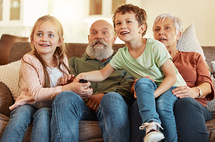 Grandparents, tv and children in a home living room streaming a web series together. Senior people, kids and television remote watching a video on a house lounge couch with a child film and movie, a Photo by Peopleimages.com