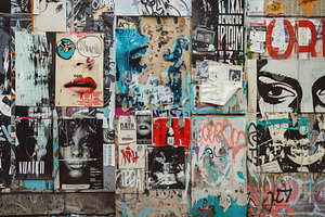 A Vibrant Urban Wall Covered With A Collage Of Posters, Graffiti, And Street Ar