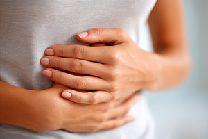 Hands on stomach indicating discomfort, a Health & Medical Photo by AlyaAnd