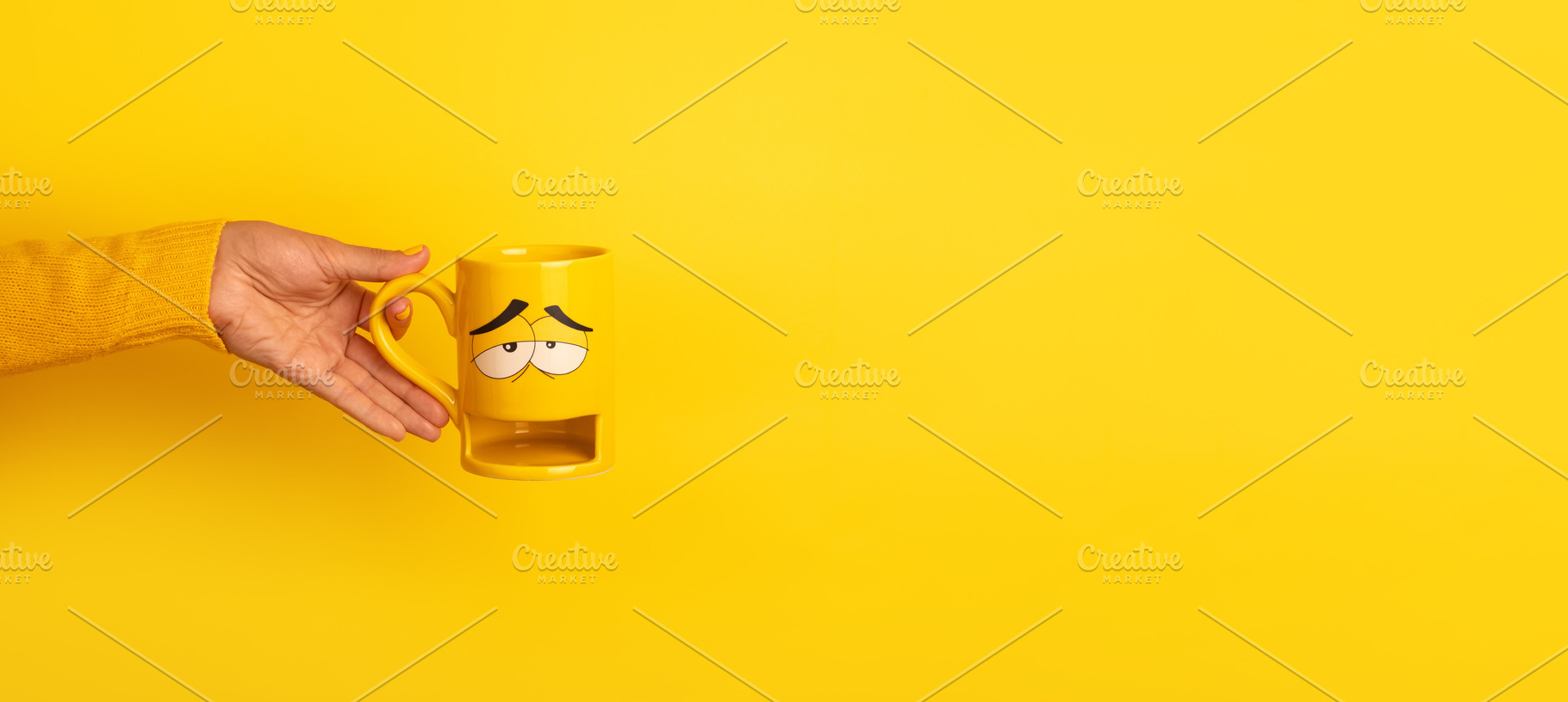 Hand in yellow sweater holding a yellow mug with a sleepy carto, a Food & Drink Photo by Ales Munt