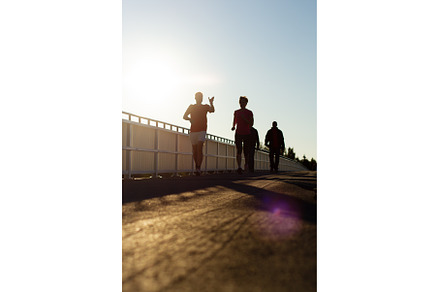 people jogging on a bridge at sunset