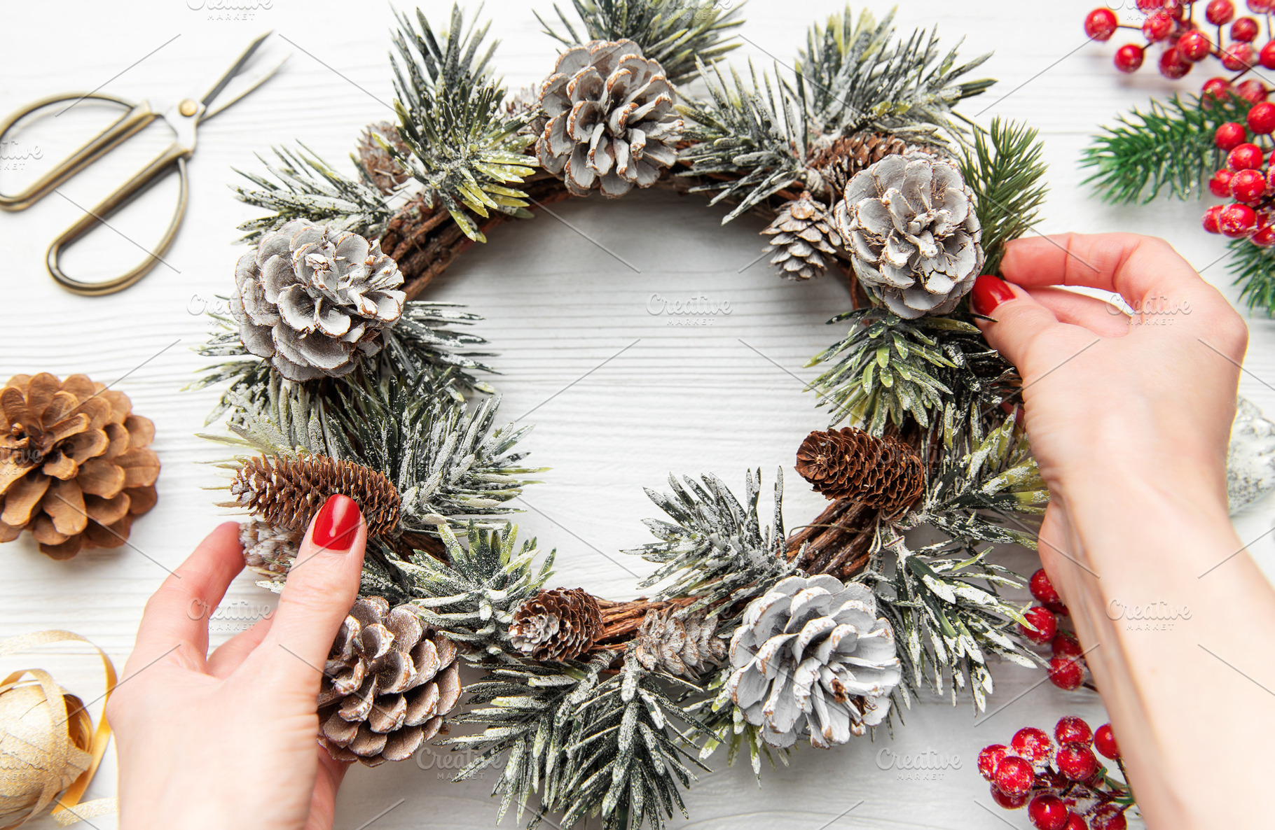 Hands decorating christmas wreath with pine cones and evergreen, a Holiday Photo by Olena Rudo