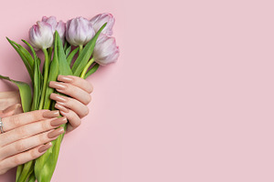 Woman holding bouquet of purple tulips showing manicure on pink, a Beauty & Fashion Photo by Olena Rudo