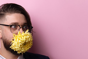 Portrait of a man with glasses wearing a yellow flower mask agai, a Person Photo by Ales Munt
