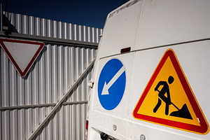 Construction vehicle with directional and warning signs on a sunny day, a Photo by AS photostudio