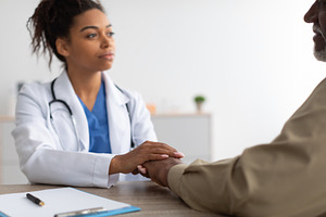 Close up of black female doctor holding male patient's hands, a Photo by Prostock-Studio
