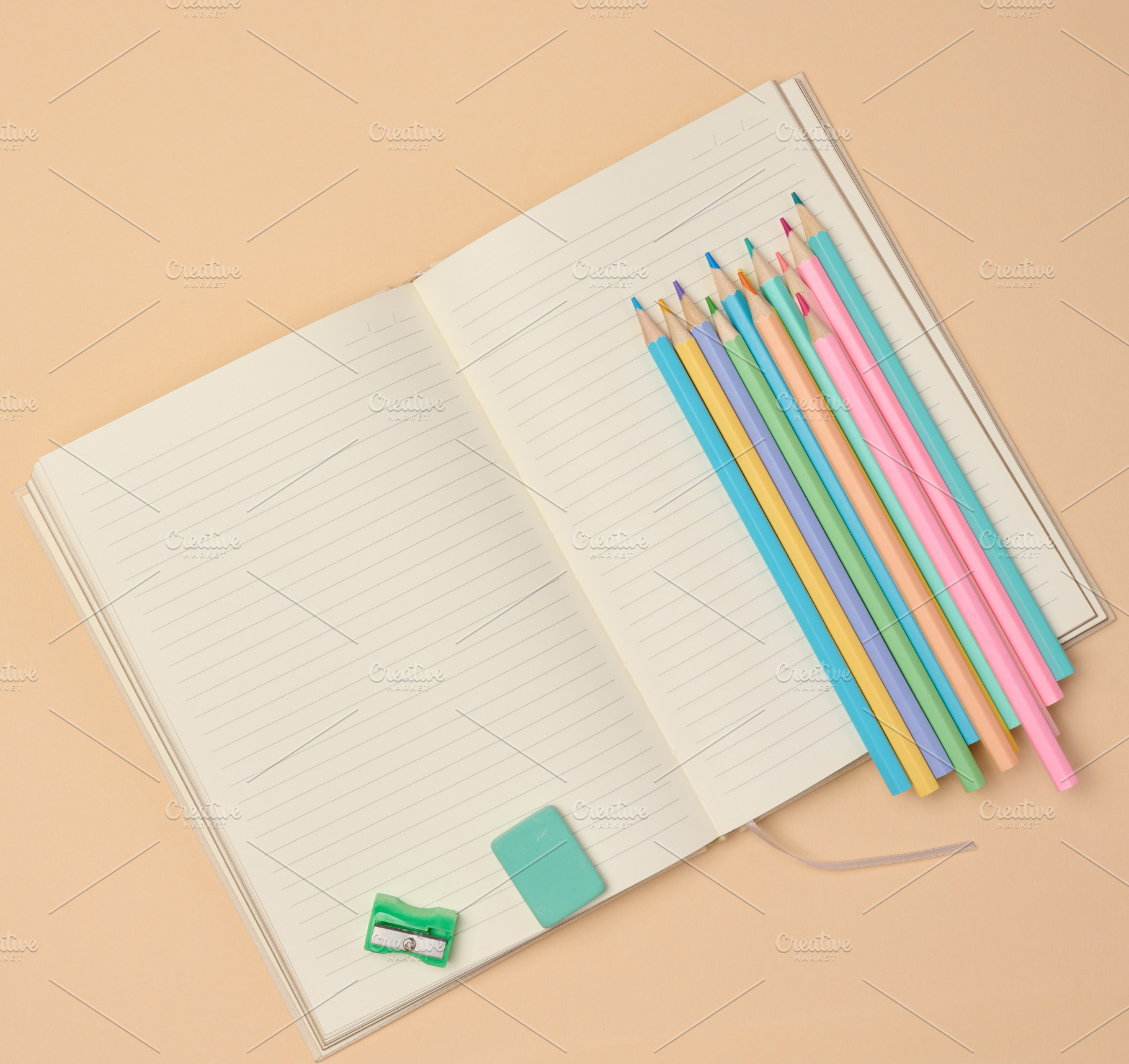 Top view of an open notebook with pastel-colored pencils, green, a School & Education Photo by ndanko