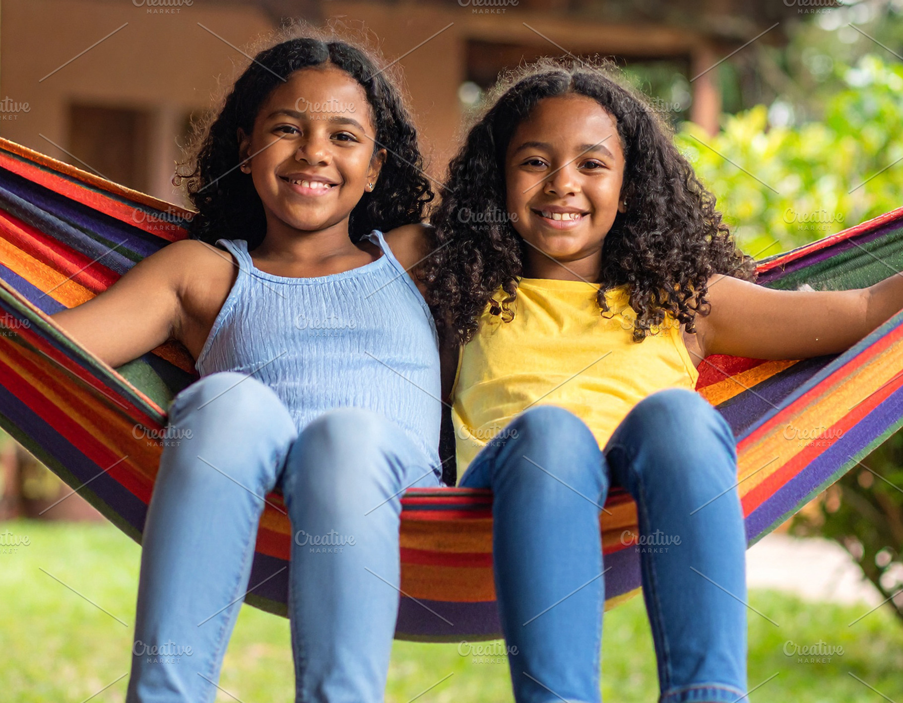 Two girls sitting together on a hammock in the backyard of a hou, a Person Photo by DanFLCreativo