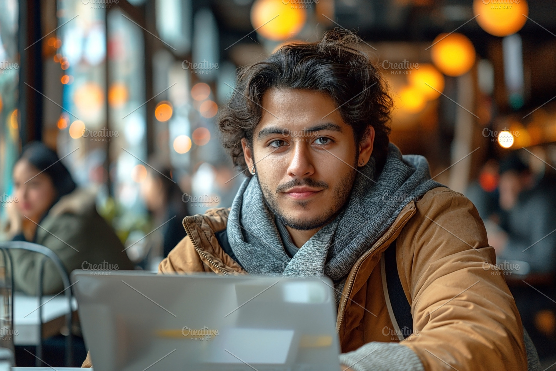 Young Hispanic man with curly hair working on a laptop in a cozy, a Person Photo by ImageMir