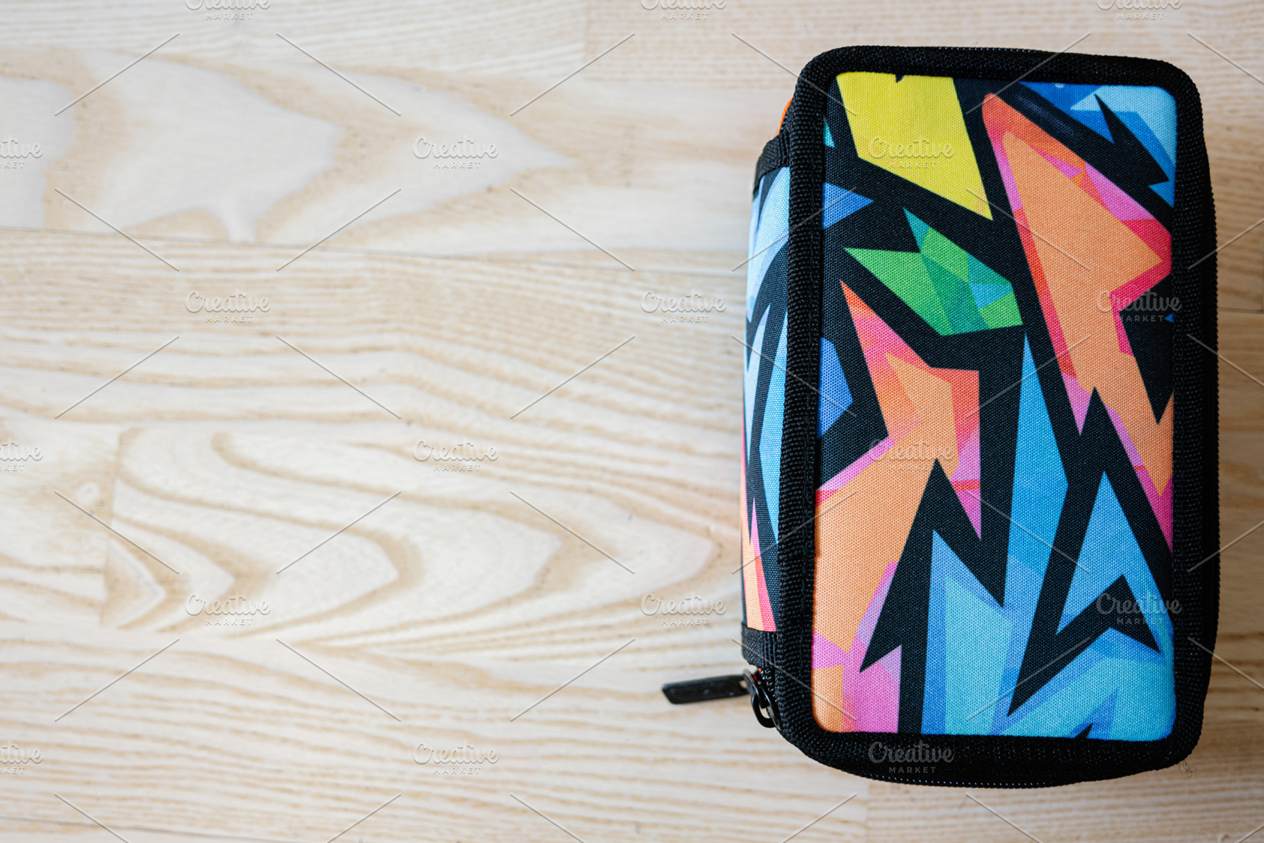 Colorful geometric zippered case on a wooden surface, a Photo by AS photostudio