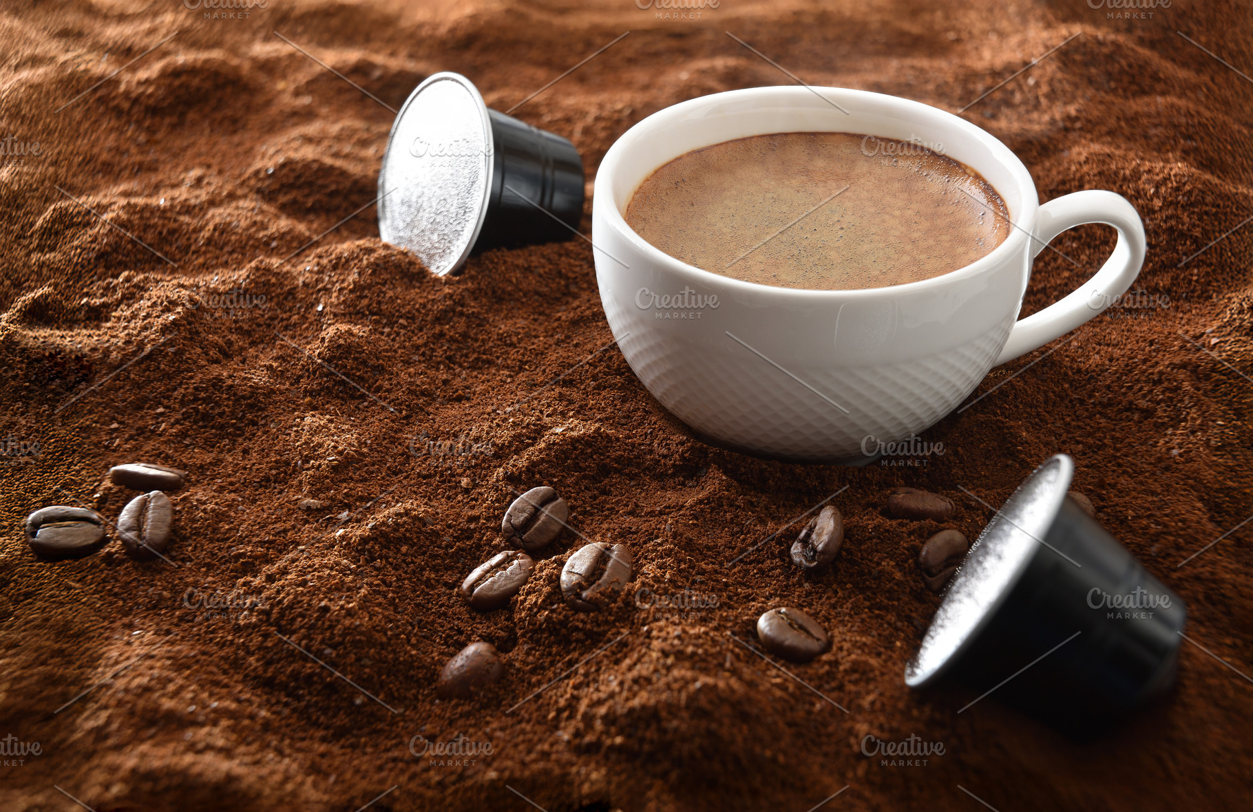Espresso cup on ground coffee with capsules around elevated view, a Food & Drink Photo by Davizro's Market