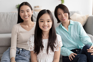 Portrait of little Asian girl spending time with ger mother and granny in livin, a Photo by Prostock-Studio