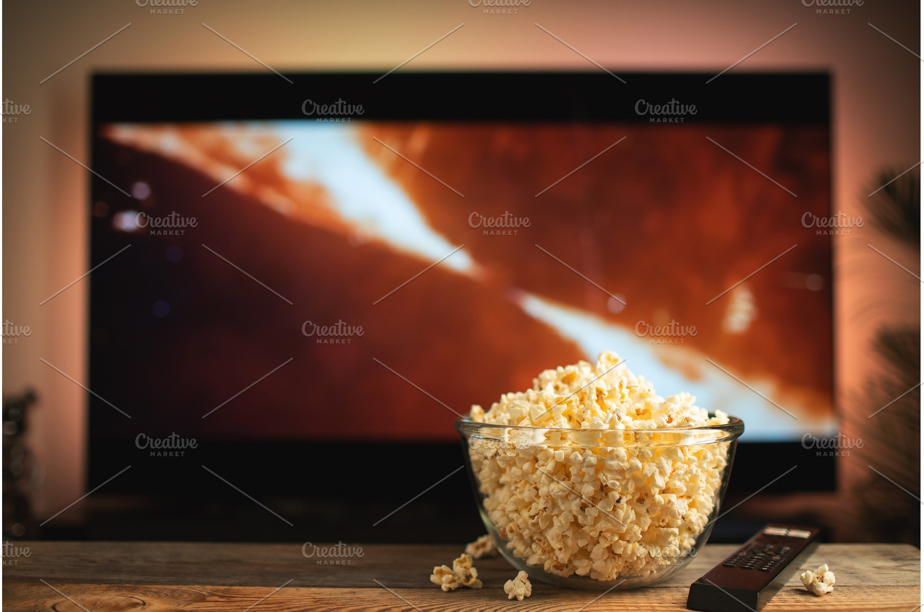 A glass bowl of popcorn and remote, a Technology Photo by Budarinphoto
