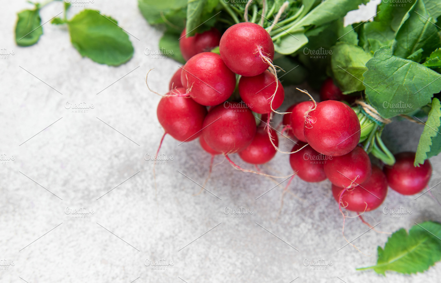 Fresh organic radishes with green leaves on concrete background, a Food & Drink Photo by Olena Rudo