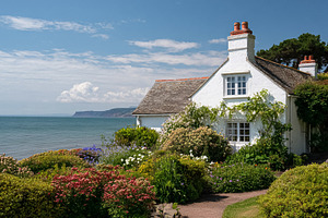 White coastal cottage with blooming garden overlooking the ocean, a Photo by Studio ANNA