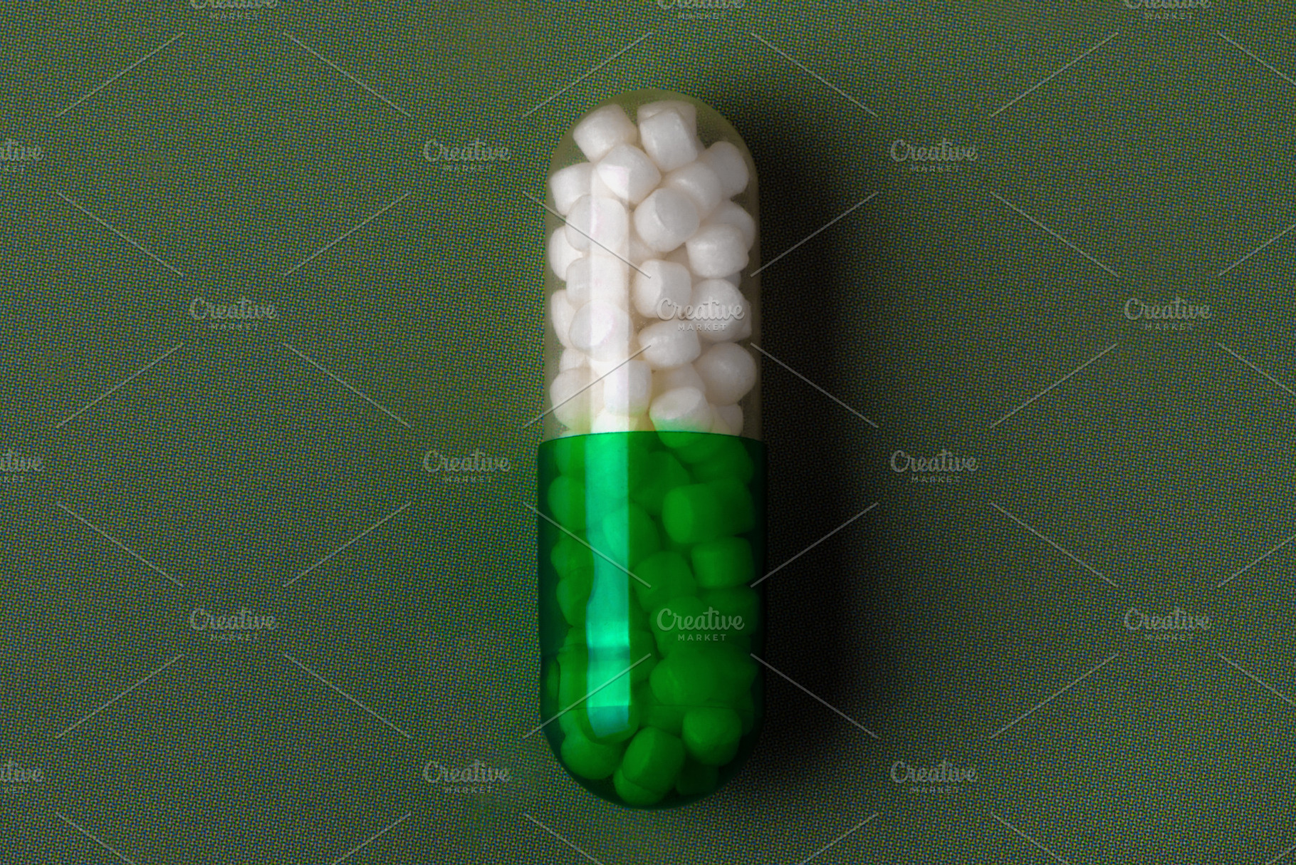 Close-up of a green and white capsule pill on a textured green background, symb, a Health & Medical Photo by Ales Munt