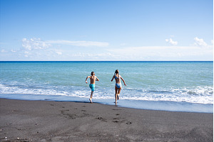Two kids running into sea on beach, a Nature Photo by HalfPoint