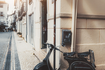 Vintage scooter, cobblestone street, a Transportation Photo by SkyNext