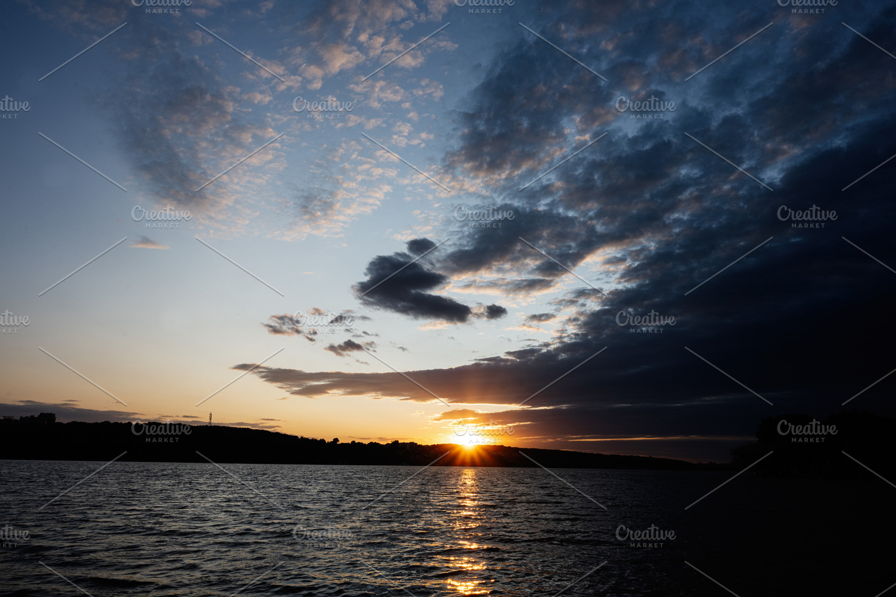 Beautiful sunset over calm water with dramatic cloud formations and serene ligh, a Photo by AS photostudio