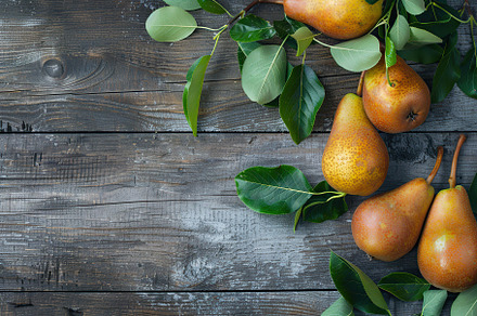 Red pears with leafs and copyspace for text on wooden table, a Food & Drink Photo by AlyaAnd