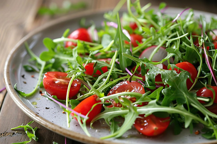 Fresh salad with microgreen, arugula and tomatoes in plate on wooden table, a Food & Drink Photo by AlyaAnd