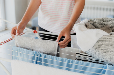 Woman hanging clean wet clothes laundry on drying rack at home laundry room, a Person Photo by Lenor4ik