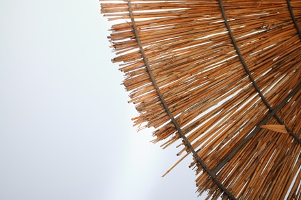 Summer straw beach umbrellas on blue, an Abstract Photo by Photo by YuraYaryna